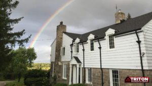 a white house with a rainbow in the sky behind it