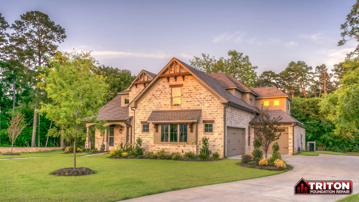 a two story brick house with trees surrounding it